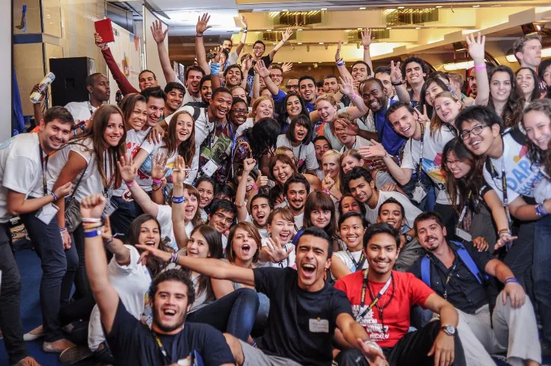 عشرات الأعضاء من AIESEC من جميع أنحاء العالم متراصون معًا ويهتفون أمام الكاميرا