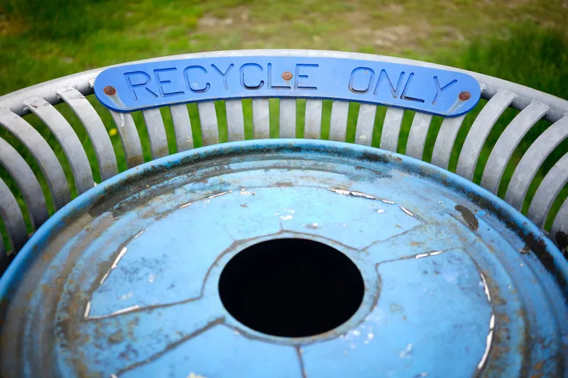 Une poubelle bleue patinée portant une plaque métallique "RECYCLE ONLY"