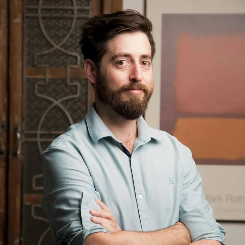 Ilan Missulawin of ClickCease, arms folded in a pale blue shirt in front of a Mark Rothko poster