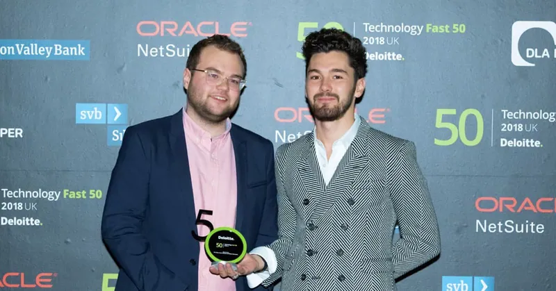 مؤسسا Paddle يحملان جائزة Deloitte Technology Fast 50 2018 UK أمام جدار صحفي